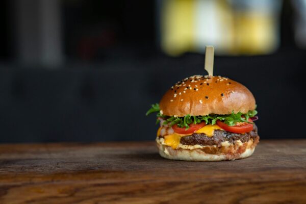 Mouth-watering cheeseburger with fresh ingredients on a wooden surface, perfect for food lovers.