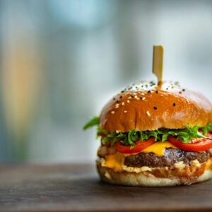 Mouthwatering cheeseburger with fresh tomatoes and lettuce on a wooden surface.