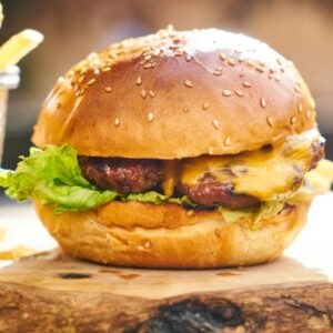 Juicy cheeseburger with crispy fries served on a wooden board, perfect fast food delight.