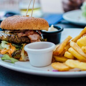 Close-up of a juicy burger and crispy fries served with sauces, perfect for a hearty meal.